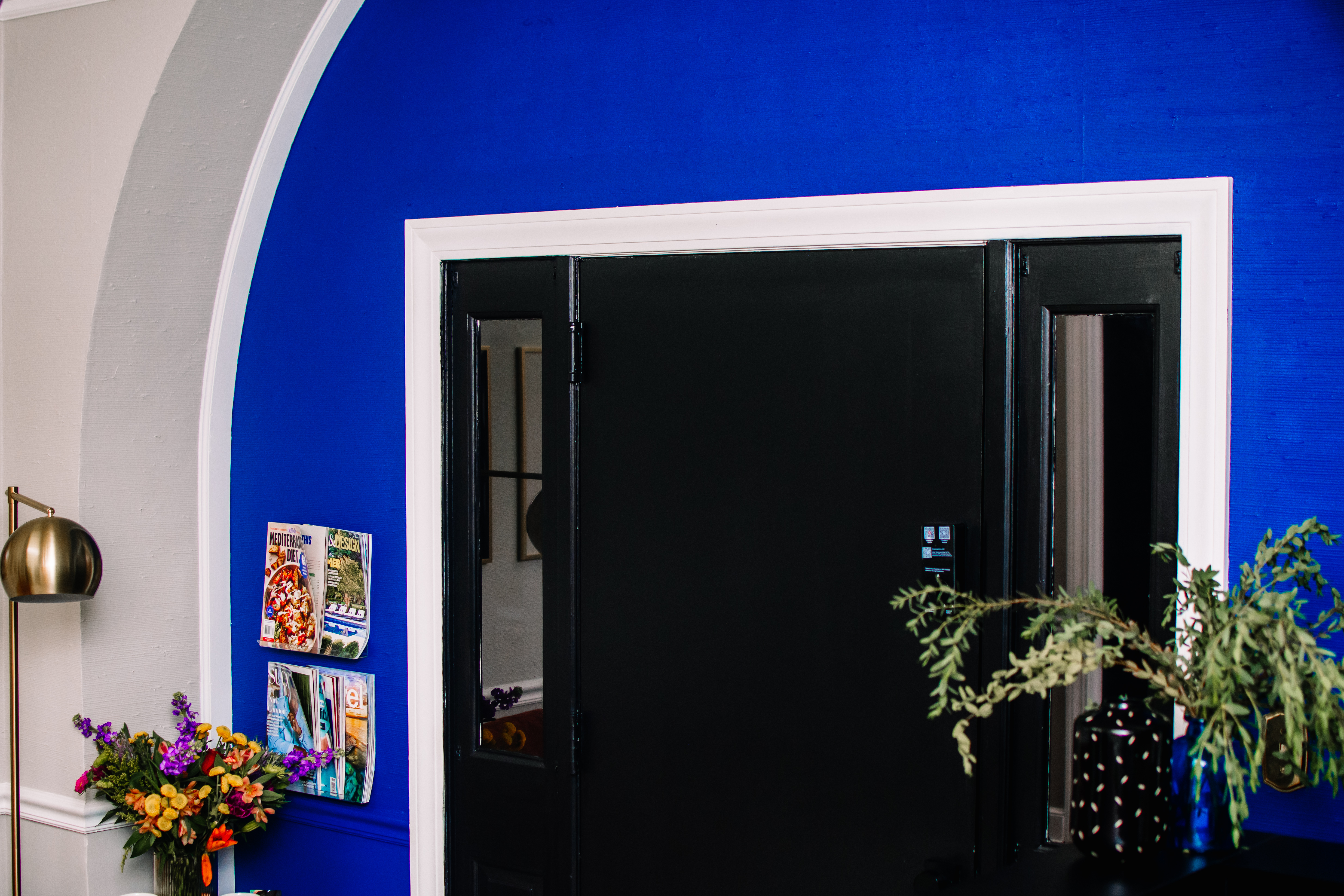 Cobalt blue accent wall with arched entry and brass floor lamp