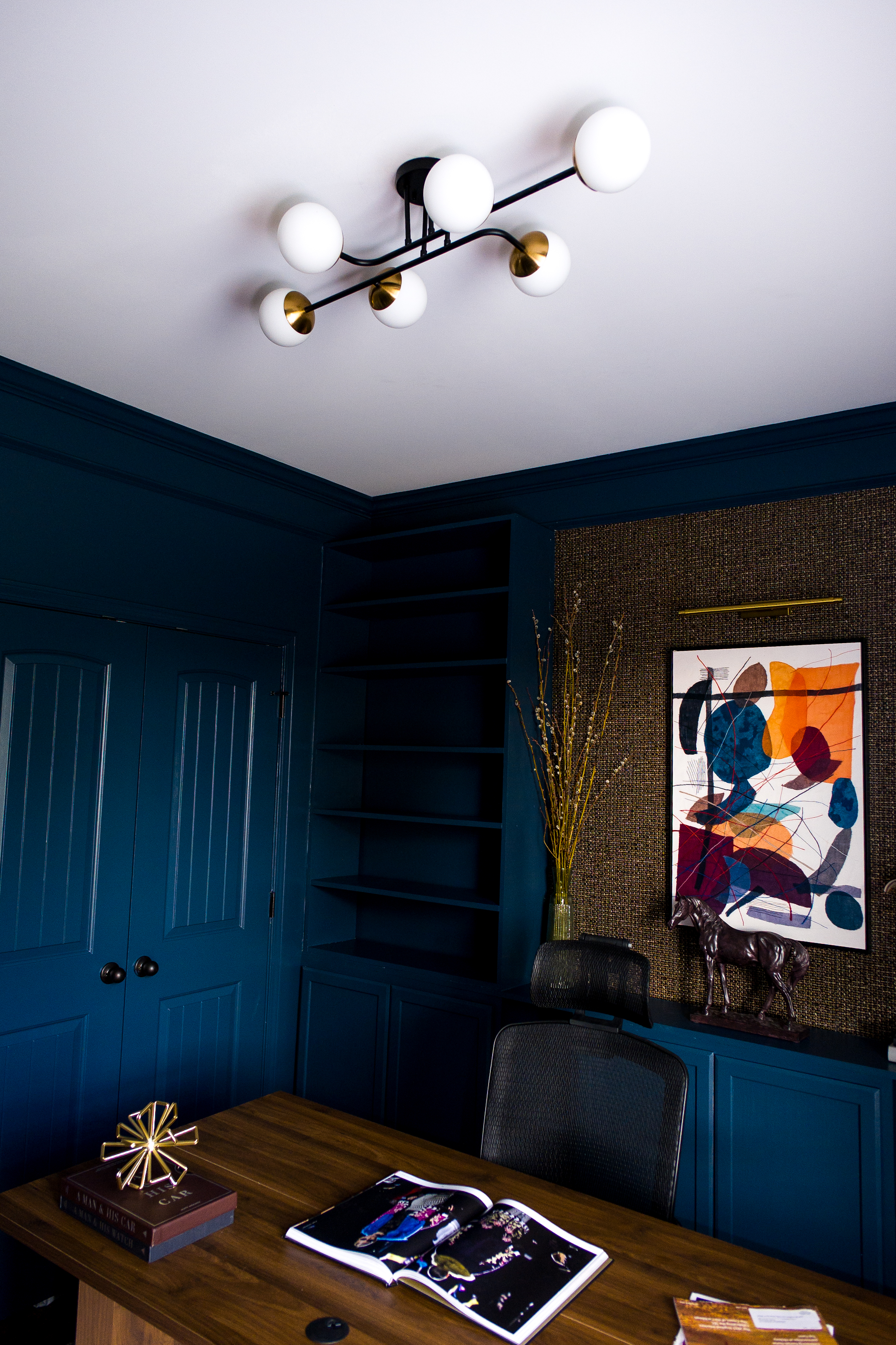 Brass lamp and art books stacked on credenza