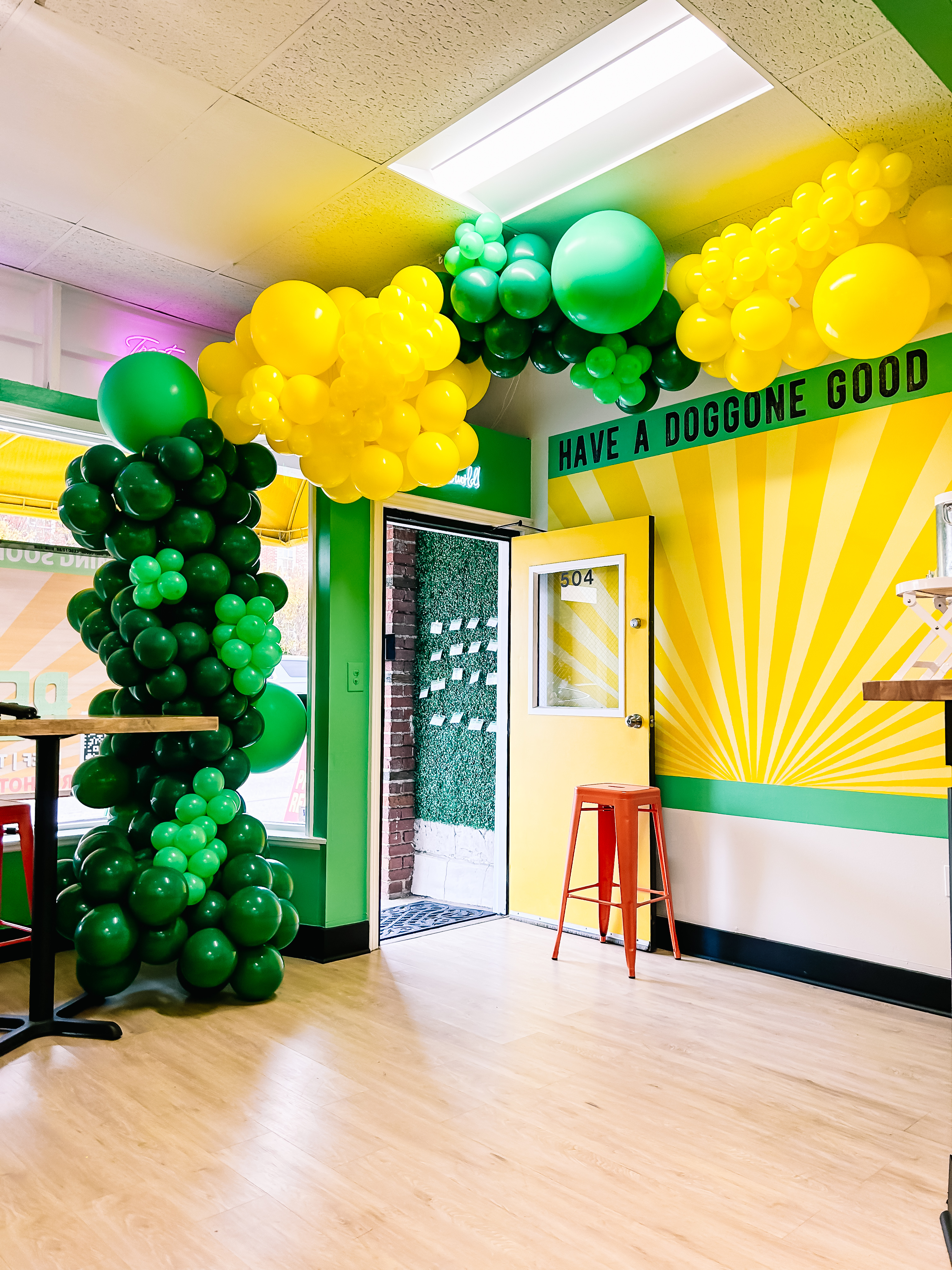 Rebel Dogs interior — sunburst mural and balloon arch at grand opening